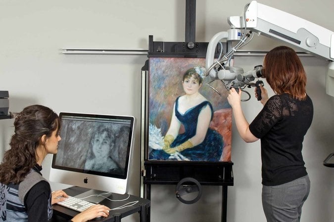 Conservators and scientists at the Art Institute of Chicago examining the pigment particles and individual brushstrokes of Renoir’s Madame Léon Clapisson (1883) with a high-power microscope and X-rays. 