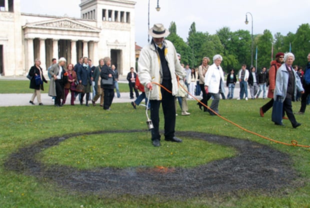 Wolfram Kastner burning a black circle into the lawn in Munich's Königsplatz square in commemoration of the Nazis' May 10, 1933 book burning. Photo: Wolfram Kastner, via the Tablet.