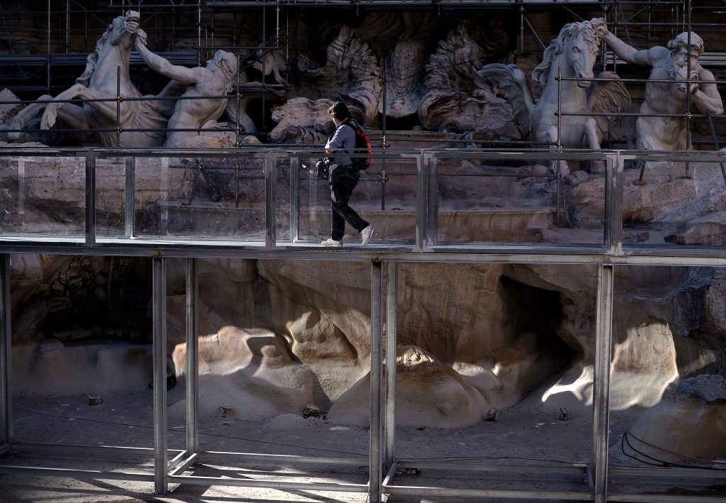 A picture shows a plexiglass bridge set up to visit the famous Trevi fountain during its restoration on June 30, 2014 in Rome. The fountain, built by Italian architect Nicola Salvi at Palazzo Poli in 1735 is fenced for restoration sponsored by Italian luxury fashion house Fendi.  Photo by Filippo Monteforte/AFP via Getty Images.