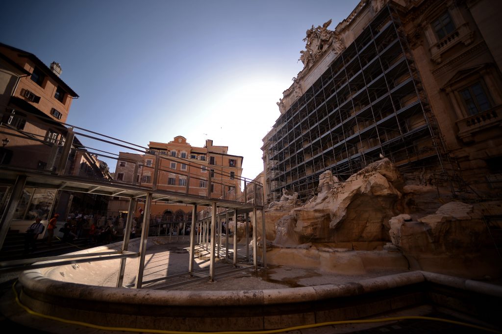 A picture shows a plexiglass bridge set up to visit the famous Trevi fountain during its restoration on June 30, 2014 in Rome. The fountain, built by Italian architect Nicola Salvi at Palazzo Poli in 1735 is fenced for restoration sponsored by Italian luxury fashion house Fendi. Photo by Filippo Monteforte/AFP via Getty Images.