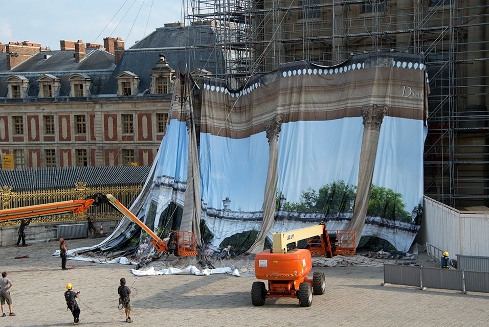 Pierre Delavie's canvas being hung to obscure scaffolding at the Palace of Versailles.