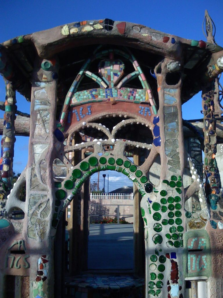 Entrance archway detail of the Watts Towers in Los Angeles, California, showing the decorative use of pottery shards, tile fragments, broken bottles, broken window glass, and seashells. Photo by JamesMadison, public domain. 