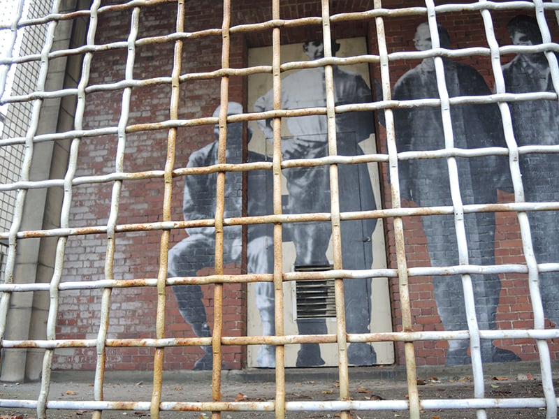 JR, "Unframed—Ellis Island" (detail). The only outdoor pasting in the installation is located in a caged porch in the former psychopathic disease ward. Photo: Sarah Cascone.