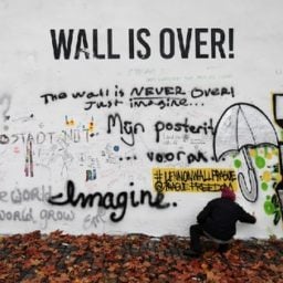 A woman walks passed the whitewashed John Lennon Wall in Prague (2014). Photo: Petr David Josek, courtesy AP Photo.