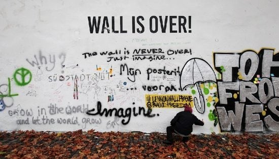 A woman walks passed the whitewashed John Lennon Wall in Prague (2014). Photo: Petr David Josek, courtesy AP Photo.