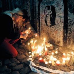 A girl lights candles at the John Lennon Wall in Prauge (1996).