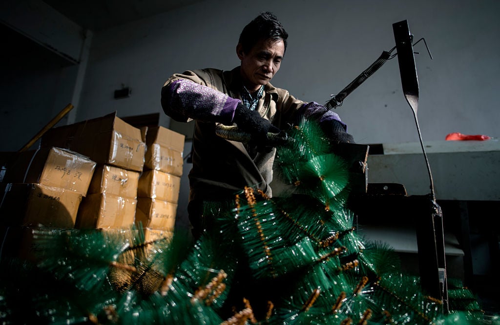 A worker cutting fake "branches" into pieces in Sun Xudan's artificial Christmas tree factory in Yiwu. Photo credit JOHANNES EISELE/AFP/Getty Images.