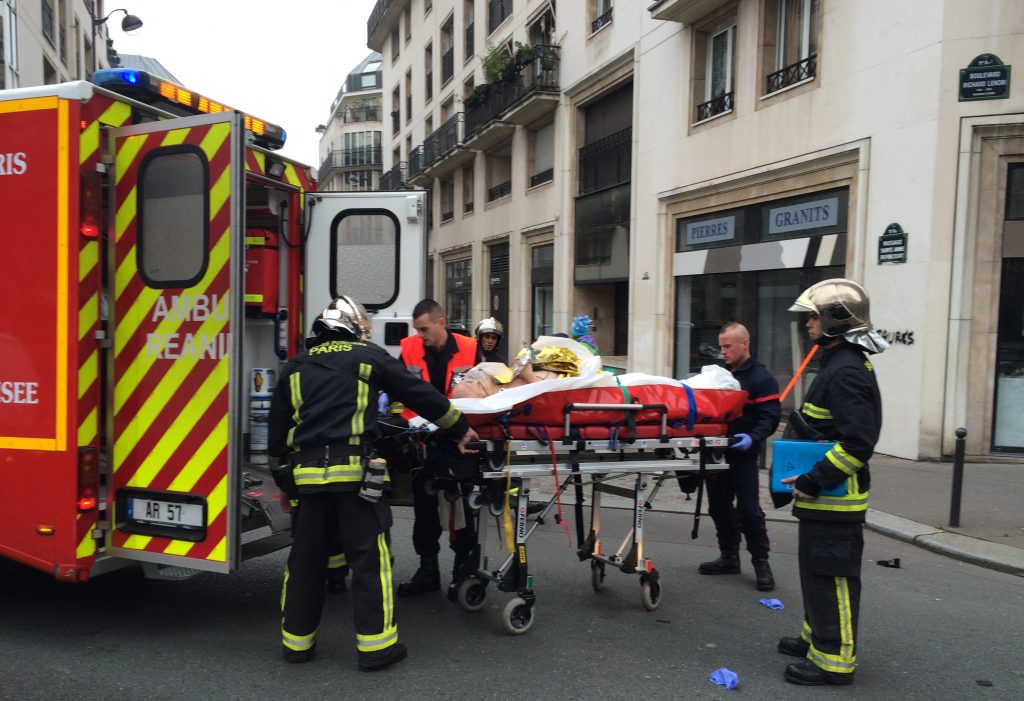 Firefighters carry an injured man on a stretcher in front of the offices of the French satirical newspaper Charlie Hebdo in Paris on January 7, 2015, after armed gunmen stormed the offices, killing 12. Photo by Philippe Dupeyrat/AFP via Getty Images.