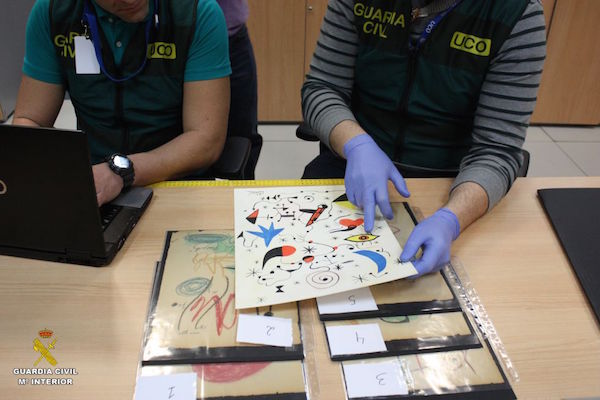 Two Civil Guard agents inspect one of the fake Joan Miró drawings. Photo courtesy of the Guardia Civil.