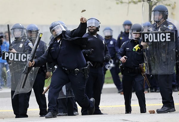 During protests-turned-riots on Monday, the day of Freddie Gray's funeral, a Baltimore police officer throws an object at the crowd. Photo: Patrick Semansky courtesy AP.