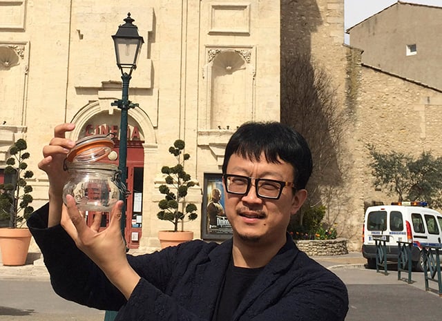 Beijing artist Liang Kegang collecting a jar's worth of fresh French air. Photo courtesy of Liang Kegang. 