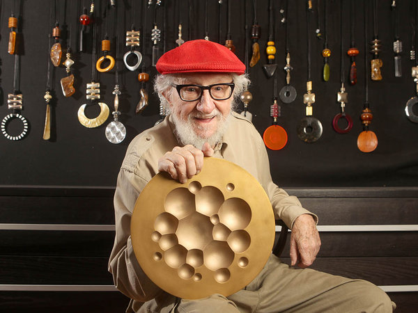 Reese Palley holding his favorite object, a limited-edition Tapio Wirkkala plate, in front of a wall of totems designed by his wife, Marilyn.  Photo: Charles Fox, courtesy the <em>Philadelphia Inquirer</em>.