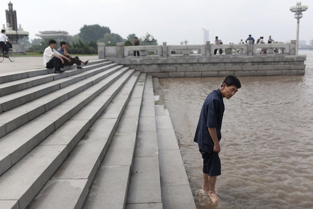 Tomas van Houtryve, A man wades into the Tae Dong river where banks are flooded high above the normal water level in Pyongyang, North Korea (2007). Photo: Tomas van Houtryve.