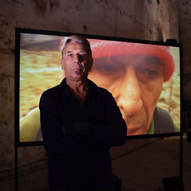 John Cale standing in front of his video installation, 2009. Photography by Prudence Cuming © The British Council.