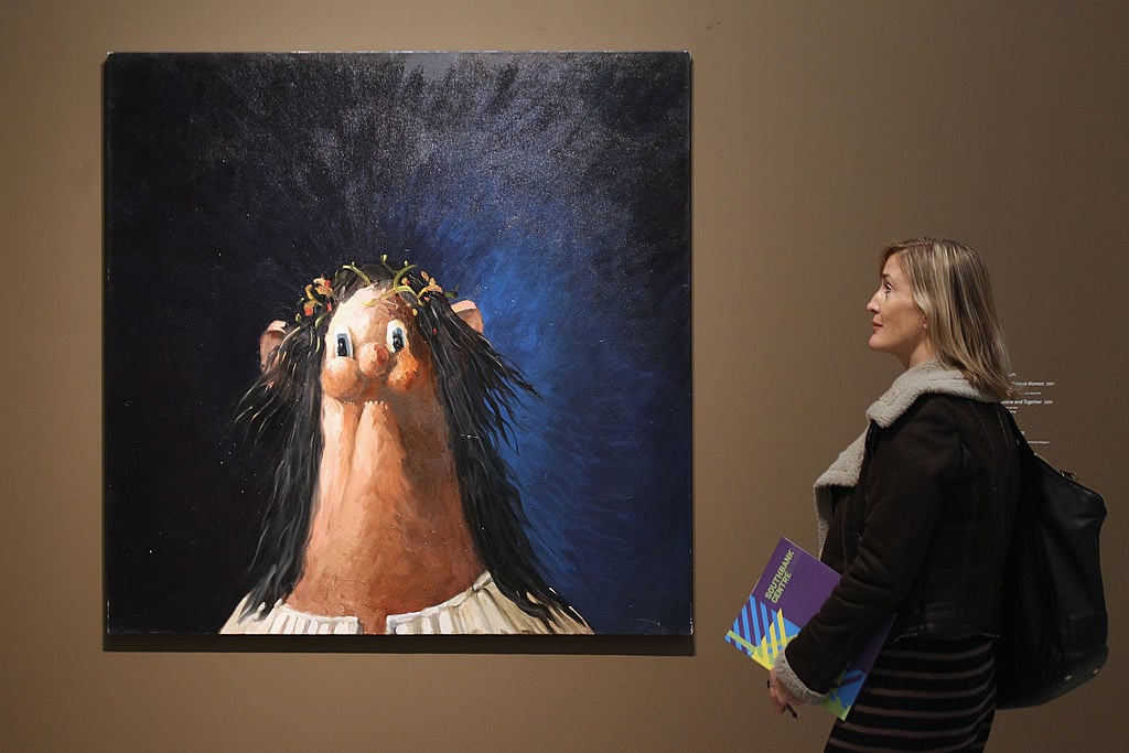 A woman views a painting by American artist George Condo entitled 'Jesus. Photo by Oli Scarff/Getty Images.
