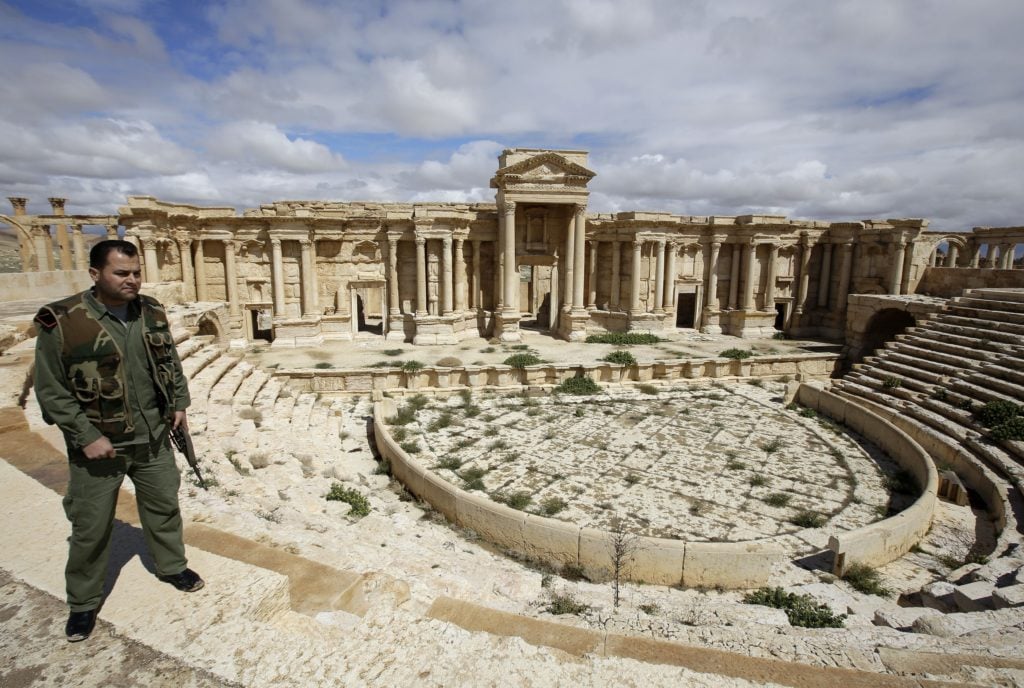A picture taken on March 14, 2014 shows a Syrian policeman patrolling the ancient oasis city of Palmyra, 215 kilometres northeast of Damascus. From the 1st to the 2nd century, the art and architecture of Palmyra, standing at the crossroads of several civilizations, married Graeco-Roman techniques with local traditions and Persian influences. Photo credit should read Josep Eid/AFP/Getty Images.