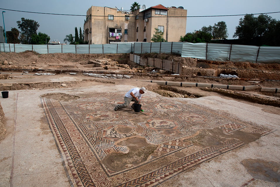 An employee of Israel's Antiquities Authority cleans the 1,700-year-old Roman-era mosaic floor discovered in Israel. Photo: AFP Photo/Menahem Kahana.