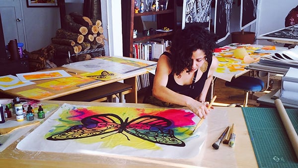 Favianna Rodriguez works on a piece in support of migrants for the Urban Justice Center. Photo: Urban Justice Center.