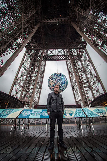 The artist posing in front of his latest installation on the Eiffel Tower, Paris. Photo: Wallpaper