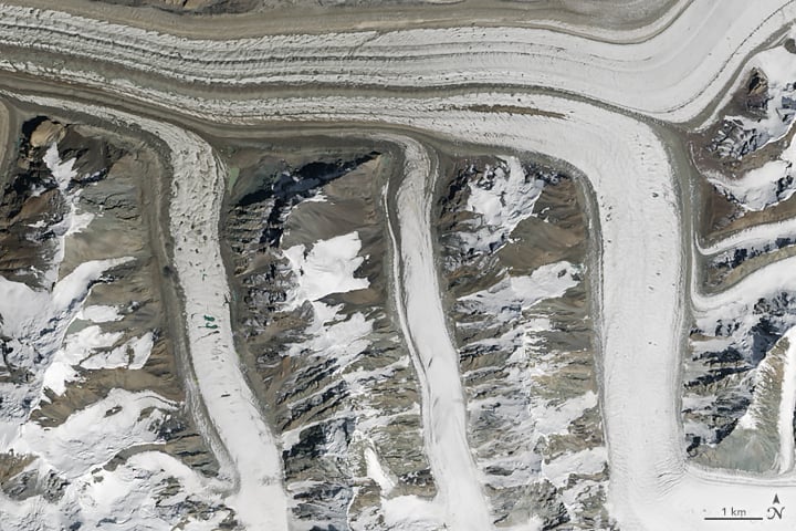 What begins with M? The meandering Mississippi. MODIS and MISR. Mumbai, Miami, and Moscow. These medial moraines merging muck and minerals for millennia! On August 14, 2015, the Operational Land Imager (OLI) on Landsat 8 captured this image of glaciers in the Tian Shan mountains in northeastern Kyrgyzstan. The trail of brown sediment in the middle of the uppermost glacier is a medial moraine, a term glaciologists use to describe sediment that accumulates in the middle of merging glaciers. Photo: courtesy NASA, caption by Adam Voiland.