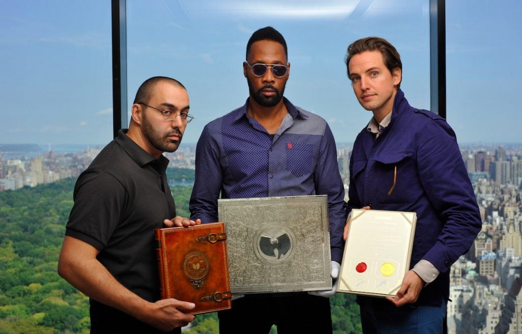 Wu-Tang Clan members Cilvaringz and RZA and Paddle8 founder Alexander Gilkes hold the book, box, and certification that come with the "Once Upon a Time in Shaolin" album. Photo courtesy of Paddle8.