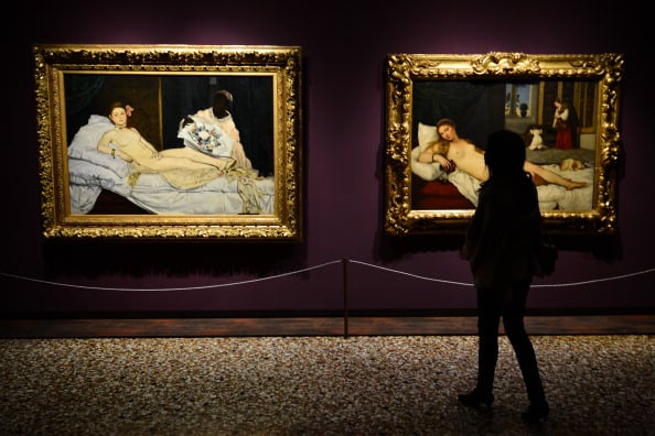 A women looks at Edouard Manet's "Olympia" (left) and Titian's "Venus of Urbino" at the exhibition "Manet Return to Venice" in 2013. <br>Image: Courtesy of GIUSEPPE CACACE/AFP/Getty Images</br>
