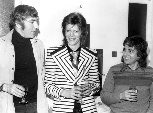 9th May 1973: Pop phenomenon David Bowie, sporting a stripy jacket with wide lapels, visits comedy duo Peter Cook (1937 - 1995), and Dudley Moore (1935 - 2002) backstage at the Cambridge Theatre in London, following the pair's show 'Behind The Fridge'. David is to appear at Earl's Court on Saturday, the first date of his British tour. Photo: Keystone/Getty Images.