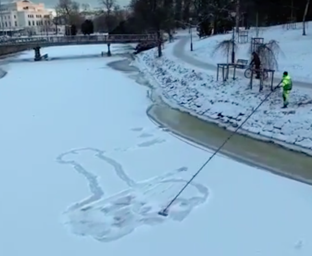 Emilian Sava used a long tool to erase the first snow penis to avoid falling through the thin ice. Photo: screenshot from Youtube user Emilian Sava.