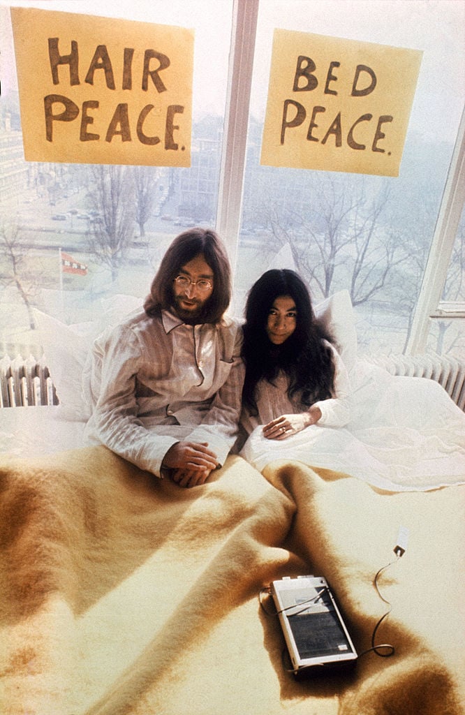 US musician John Lennon (R) and his japanese wife Yoko Ono (L) pose for photographers in Amsterdam 27 March 1969. The honeymoon couple is spending a week in bed at Hilton Hotel to protest against world violence. (FILM) AFP PHOTO (Photo credit should read -/AFP/Getty Images)