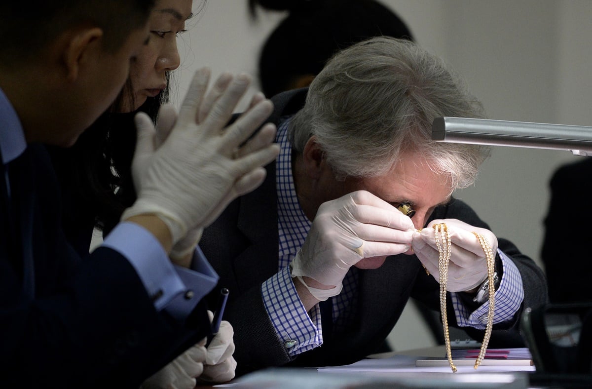 Christie's and Sotheby's auction house appraiser David Warren (R) examines diamond jewellery seized by the Philippine government from former first lady Imelda Marcos, at the Central Bank headquarters in Manila on November 24, 2015. Philippine authorities on November 24 showcased a dazzling collection of jewels seized from the family of the late dictator Ferdinand Marcos appraised in preparation for a possible auction. The long-hidden collection, seized in three batches after Marcos was overthrown in 1986, also provides a stark look at how the Marcos family enriched itself while the nation sank deeper into poverty. AFP PHOTO / NOEL CELIS / AFP / NOEL CELIS (Photo credit should read NOEL CELIS/AFP/Getty Images)