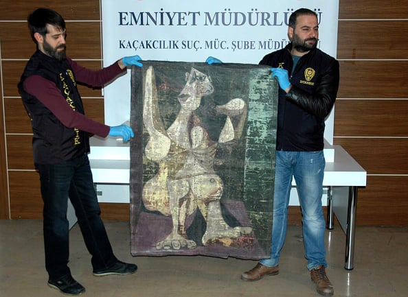 Turkish police from the Istanbul Police Department Anti-Smuggling and Organized Crime Unit, hold-up an original painting by Pablo Picasso. Photo: STR/AFP/Getty Images