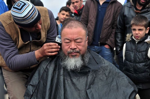 A migrant barber shaves Ai Weiwei's head at a makeshift camp at the Greek-Macedonian border, near the Greek village of Idomeni on March 17, 2016.Photo: Sakis Mitrolidis/AFP/Getty Images.