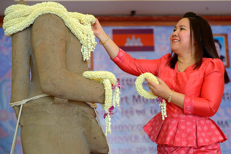 A Cambodian woman places a garland around a 10th-century sandstone sculpture of the Hindu god Rama after returning from the Denver Art Museum in the United States during a ceremony at the Council of Ministers in Phnom Penh on March 28, 2016. 62 - A one-inch-high torso, which was stolen in the 1970s from the Koh Ker temple site near the famous Angkor Wat complex, was handed over by the museum, which had owned it since 1986. Photo: Tang Chhin Sothy / AFP / Getty Images.