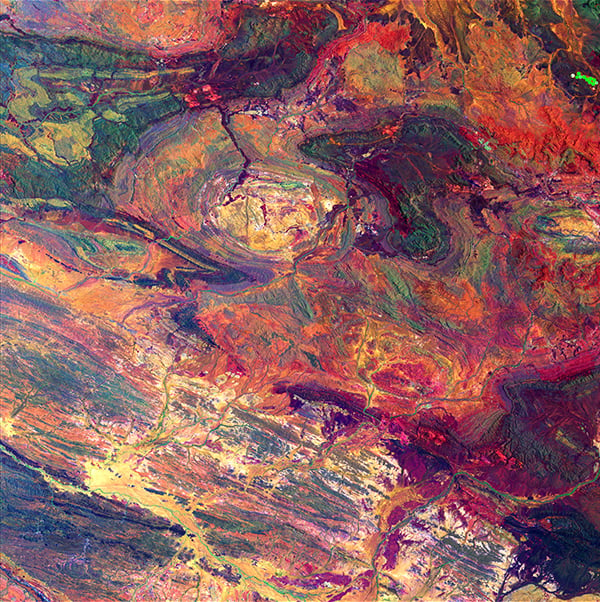 <em>Australian Iron Ore</em>, "Earth as Art," December 19, 2014. <br>Within the Hamersley Iron Province in Western Australia, Landsat's shortwave infrared and near-infrared detectors highlight different types of rock. The oval in the upper center part of the image is a geological feature called Rocklea Dome. The dark meanders within the dome are channel iron deposits. <br>Photo: USGS.