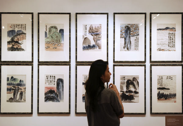 Caption:In a picture taken on October 6, 2012, a woman inspects artwork by Chinese artist Qi Baishi entitled 'Landscapes' during a China Guardian auction preview in Hong Kong. China Guardian Auctions, China's oldest auction house, held a sale on October 7 of more than 300 Chinese paintings including modern masters that is expected to fetch about 24 million USD. <br>Photo: DALE de la REY/AFP/GettyImages