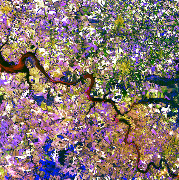 <em>Tessera Mosa</em>, "Earth as Art," September 2, 2014. <br>The Tietê River snakes across this tessera mosaic of multicolored shapes near Ibitinga, Brazil. Fields of sugarcane, peanuts, and corn vary in their stages of development. Lavender, purple, and bright blue indicate actively growing crops. Light yellow or white indicate little or no vegetation growth. The splotches of dark mustard yellow are urban areas. <br>Photo: USGS.