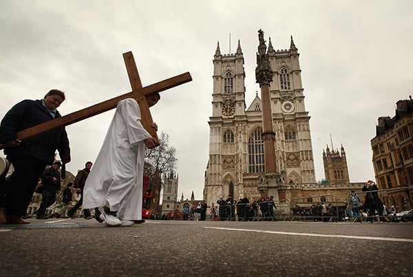 A man from the Passage, a day center for homeless people, carries a cross past Westminster Abbey on April 10, 2009 in London. <br>Photo: Peter Macdiarmid/Getty Images.