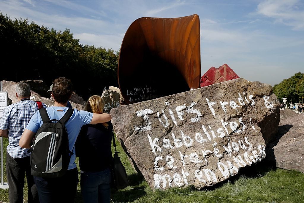 People look at the grafitti inscribed artwork by British-Indian artist Anish Kapoor entitled Dirty Corner in the gardens of the Chateau de Versailles in Versailles on September 11, 2015, a day after the artwork was emblazoned with grafitti for a third time. Courtesy of Versailles Patrick Kovarik/AFP/Getty Images)