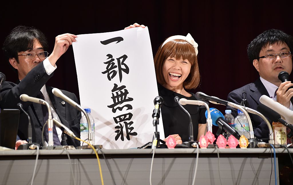 Japanese artist Megumi Igarashi (C) displays a sign reading "a part is not guilty" during a briefing with her lawyers in Tokyo on May 9, 2016. A Japanese artist who makes objects shaped like her vagina was convicted on May 9 after a high-profile obscenity trial, in a decision likely to reignite accusations of heavy-handed censorship. / AFP / KAZUHIRO NOGI Courtesy of KAZUHIRO NOGI/AFP/Getty Images.