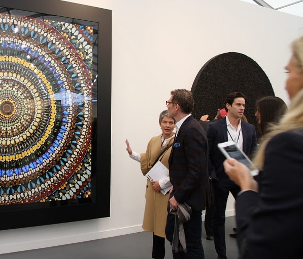 An advisor talks to celebrity chef Bobby Flay at Frieze New York at Gagosian Gallery's Damien Hirst booth. Courtesy of Sarah Cascone.