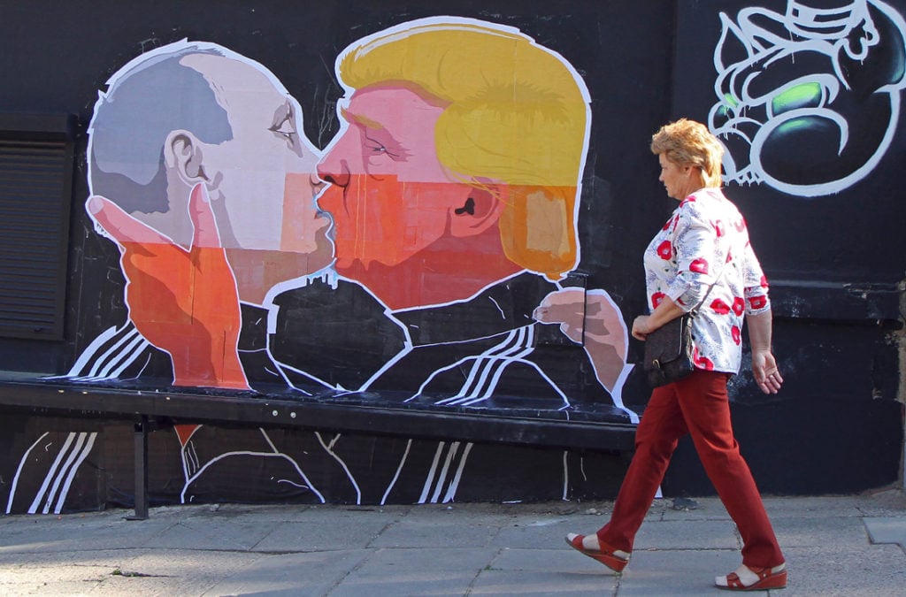 A woman walks past a mural on a restaurant wall depicting US Presidential hopeful Donald Trump and Russian President Vladimir Putin greeting each other with a kiss in the Lithuanian capital Vilnius on May 13, 2016. Photo Petras Malukas /AFP/Getty Images.