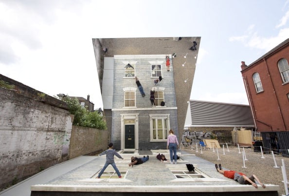 People interact with a large-scale installation art piece by Argentinian artist Leandro Erlich, entitled 'Dalston House', in East London on June 25, 2013. AFP PHOTO/JUSTIN TALLIS Photo credit should read JUSTIN TALLIS/AFP/Getty Images