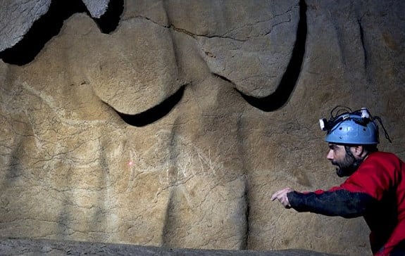 Archaeologist Diego Garate with some of the cave paintings he helped discover in Spain's Atxurra cave. Courtesy of AFP/Getty Images.