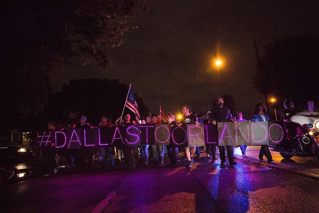 TOPSHOT - Mourners hold an LED sign reading "Dallas To Orlando" as they march during a vigil in Dallas, Texas, on June 12, 2016, for victims of the attack at Orlando's Pulse Nightclub in Orlando, Florida. Fifty people died when a gunman allegedly inspired by the Islamic State group opened fire inside a gay nightclub in Florida, in the worst terror attack on US soil since September 11, 2001. / AFP / Laura Buckman (Photo credit should read LAURA BUCKMAN/AFP/Getty Images)