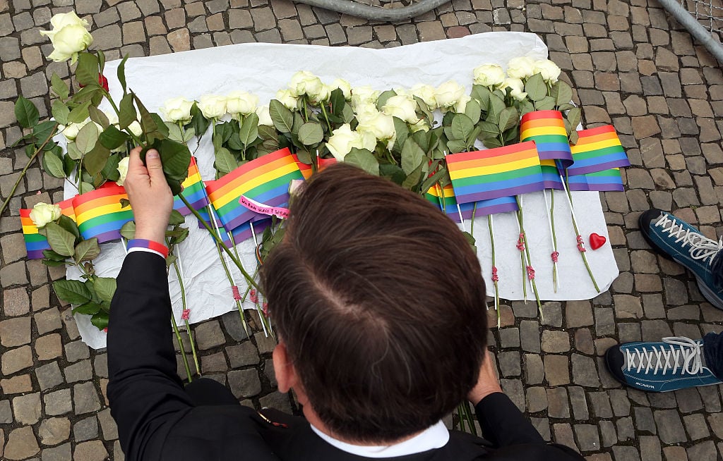 A visitor places flowers at a makeshift memorial during a vigil for victims of a shooting at a gay nightclub in Orlando, Florida the previous day, in front of the United States embassy on June 13, 2016 in Berlin, Germany. Fifty people were killed and at least as many injured during a Latin music event at the Pulse club in the deadliest mass shooting in the United States and the worst terror attack there since 9/11. The American-born gunman had pledged allegiance to ISIS, though officials have yet to find conclusive evidence of his having any direct connection with foreign extremists. Photo by Adam Berry/Getty Images.