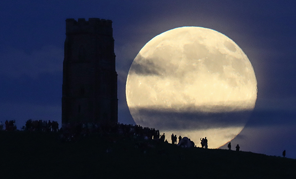 The Summer Solstice full moon, dubbed the Strawberry Moon, rises above Glastonbury Tor in Somerset, England on June 20, 2016. Courtesy photographer Matt Cardy/Getty Images.