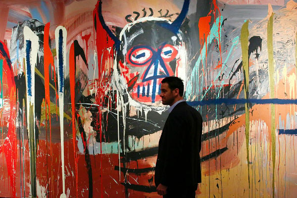 Loic Gouzer of Christie's stands next to the artwork Untitled by Jean-Michel Basquiat. Courtesy of KENA BETANCUR/AFP/Getty Images.