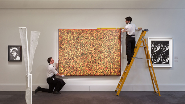 Keith Haring, <em>The Last Rainforest</em> (1989) being installed at Sotheby's London next to Andy Warhol, <em>Four Marilynd (Reversal Series)</em> 1979–86. Courtesy of Sotheby's London. 