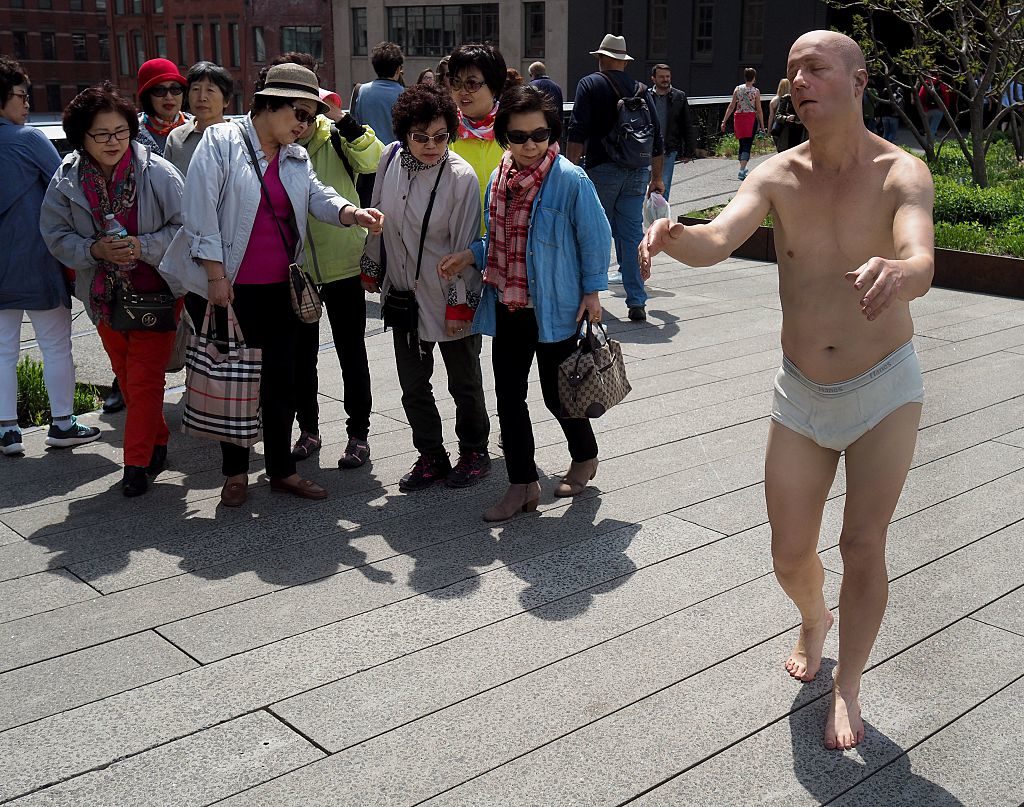 Tourists stop to look at artist Tony Matelli's "Sleepwalker" (2014), a lifelike figure is of a man in white briefs wandering in his sleep with outstretched arms installed on the Highline as part of the show "Wanderlust" April 25, 2016. Courtesy of TIMOTHY A. CLARY/AFP/Getty Images.