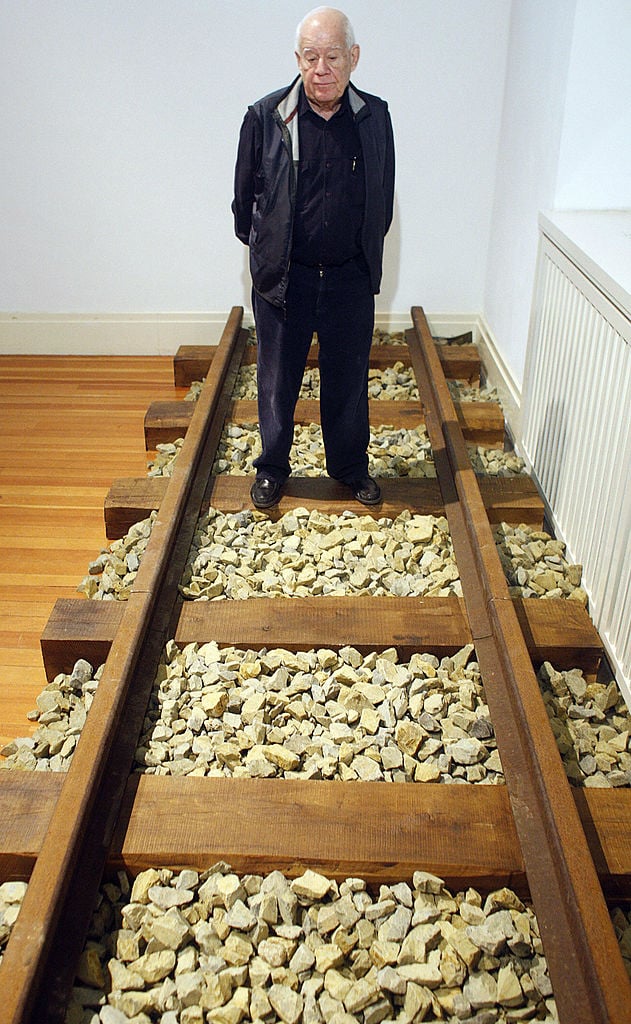 Israeli artist Dani Karavan poses on March 13, 2008 on a railtrack part of his installation "Homage to the Prisoners of Gurs" during the presentation of his exhibition "Dani Karavan Retrospective" running from March 14 to June 01 at the Martin-Gropius-Bau Museum in Berlin. Courtesy of MICHAEL KAPPELER/AFP/Getty Images.